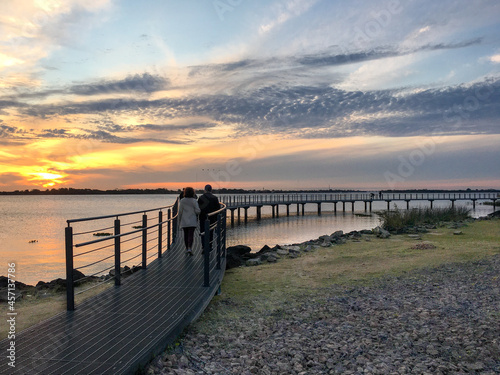 a couple walking by a lake at sunset