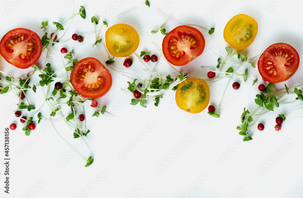 Close up composition of cutted red and yellow cherry tomatoes with microgreens and pink pepper on light background Close up composition of cutted red and yellow cherry tomatoes with microgreens and pink pepper on light background