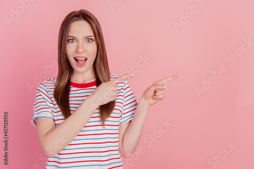 Portrait of excited promoter lady direct forefingers empty space on pink background © Tetiana