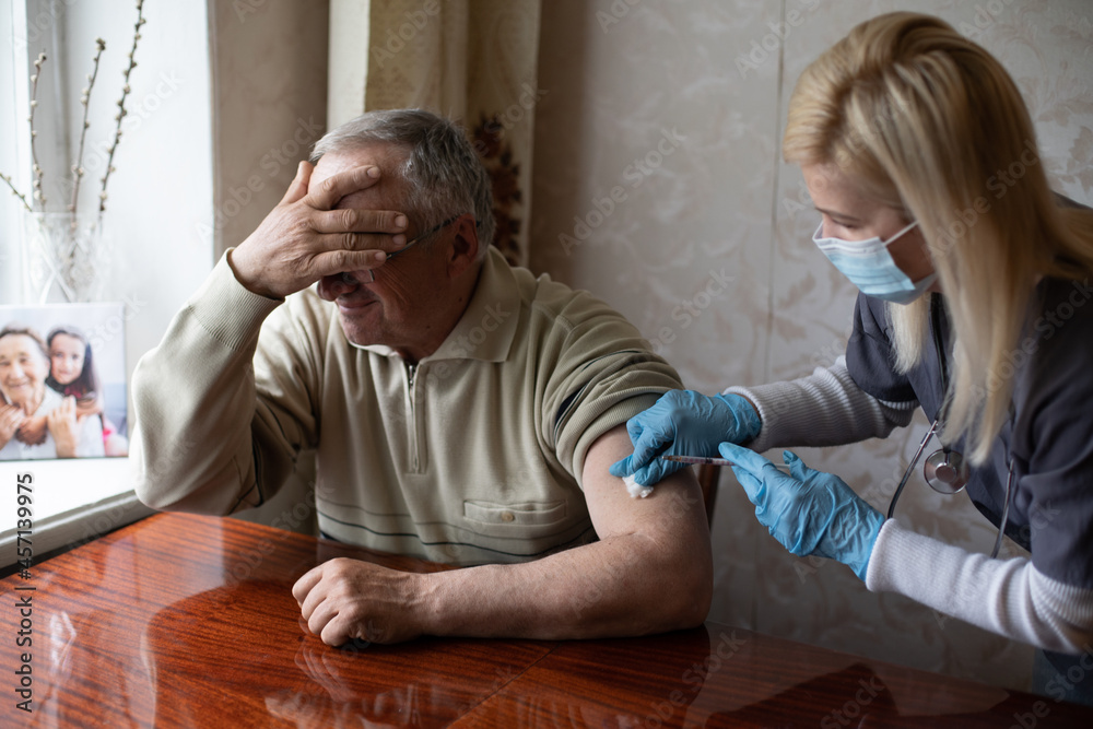 Doctor preparing vaccination shot to elderly patient by holding syringe at home - concept of home health check to seniors during coronavirus covid-19 pandemic Doctor preparing vaccination shot to elderly patient by holding syringe at home - concept of home health check to seniors during coronavirus covid-19 pandemic