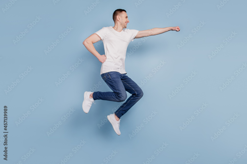 Full size profile side photo of excited man jumping fly air superhero isolated over blue color background