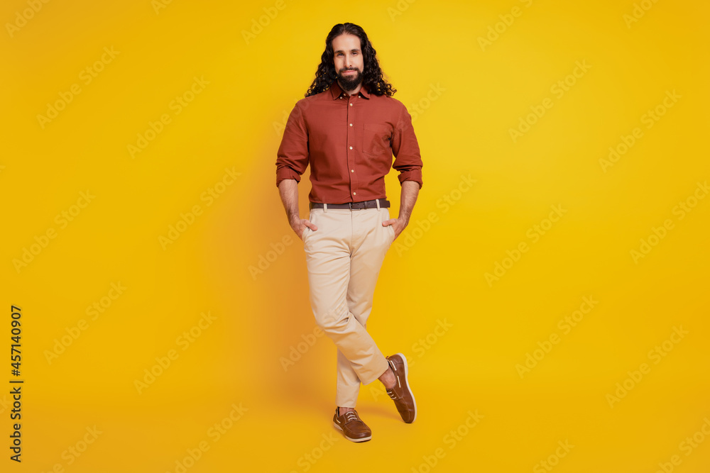 Fototapeta premium Portrait of confident masculine guy hands pockets posing on yellow background