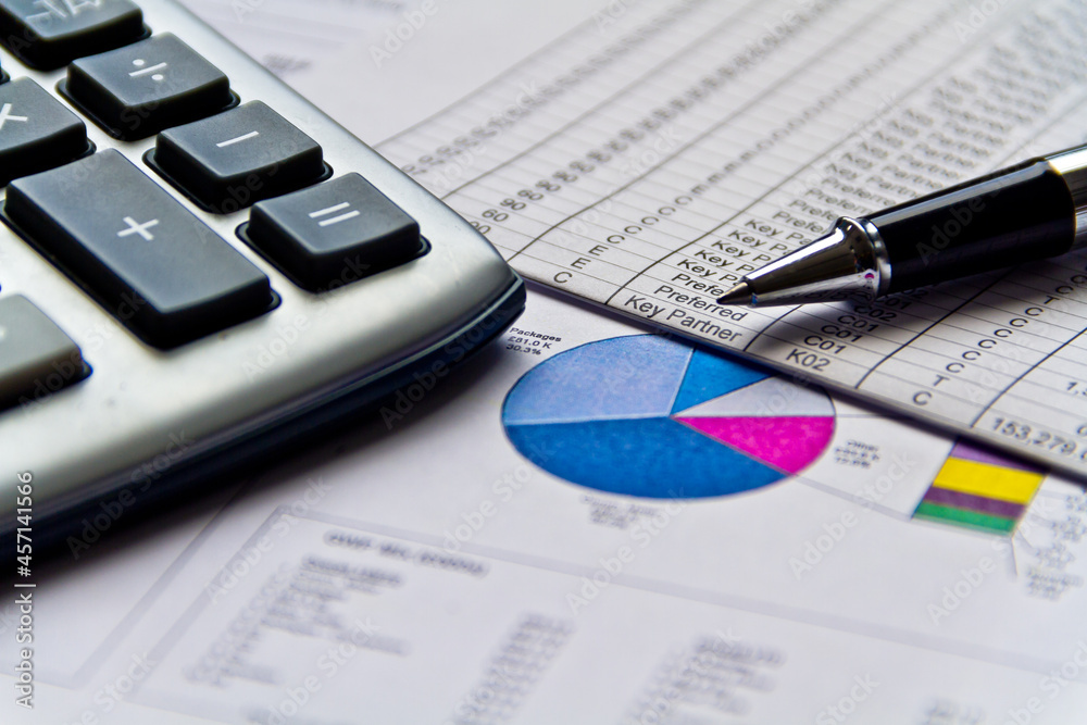 Financial charts and graphs on table with calculator and ballpoint pen. Stock market or trading charts. Finance markets concept. Financial charts and graphs on table with calculator and ballpoint pen. Stock market or trading charts. Finance markets concept.