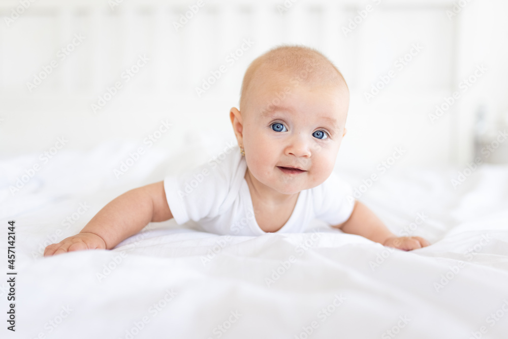 Portrait of cute and smiling four month old baby girl playing on the bed in her room. Happy and dry kid. Portrait of cute and smiling four month old baby girl playing on the bed in her room. Happy and dry kid.