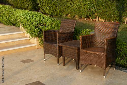 rattan furniture for relaxing in the park. Chairs and table on a background of green bushes