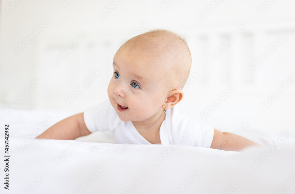 Portrait of cute and smiling four month old baby girl playing on the bed in her room. Happy and dry kid. Portrait of cute and smiling four month old baby girl playing on the bed in her room. Happy and dry kid.