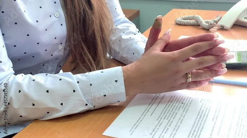 Hands of a girl in a light blouse with a light manicure and a gold ring close-up
