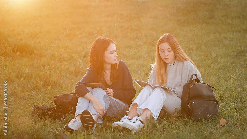 Φωτογραφία Two teenage students friends girls at the park of university with books and tabl