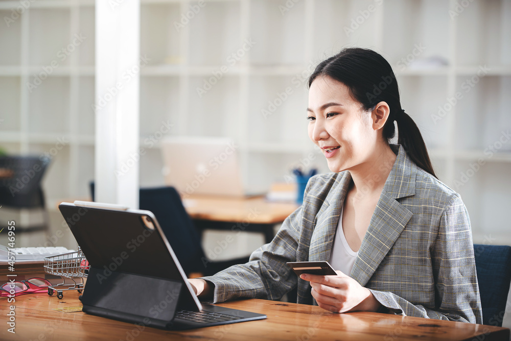 girl holding a credit card and using a laptop Business woman working from home . online shopping, ecommerce, internet banking, spend money, work from home concept. girl holding a credit card and using a laptop Business woman working from home . online shopping, ecommerce, internet banking, spend money, work from home concept.