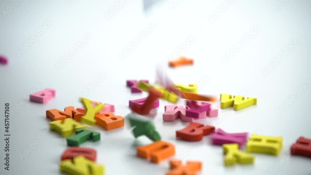 Spinning colored letters on a white table. Close-up conceptual shot of alphabet letters falling on a white background. Representing memory loss, brainstorming, writing, amnesia. Spinning colored letters on a white table. Close-up conceptual shot of alphabet letters falling on a white background. Representing memory loss, brainstorming, writing, amnesia.
