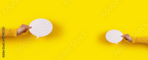 Photographie two talk bubbles speech icon in hand over yellow background, panoramic layout