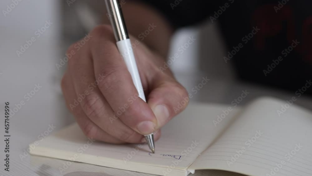 Male hand writing on a piece of paper. Writing essay or letters. Doing homework. Learning concept Male hand writing on a piece of paper. Writing essay or letters. Doing homework. Learning concept
