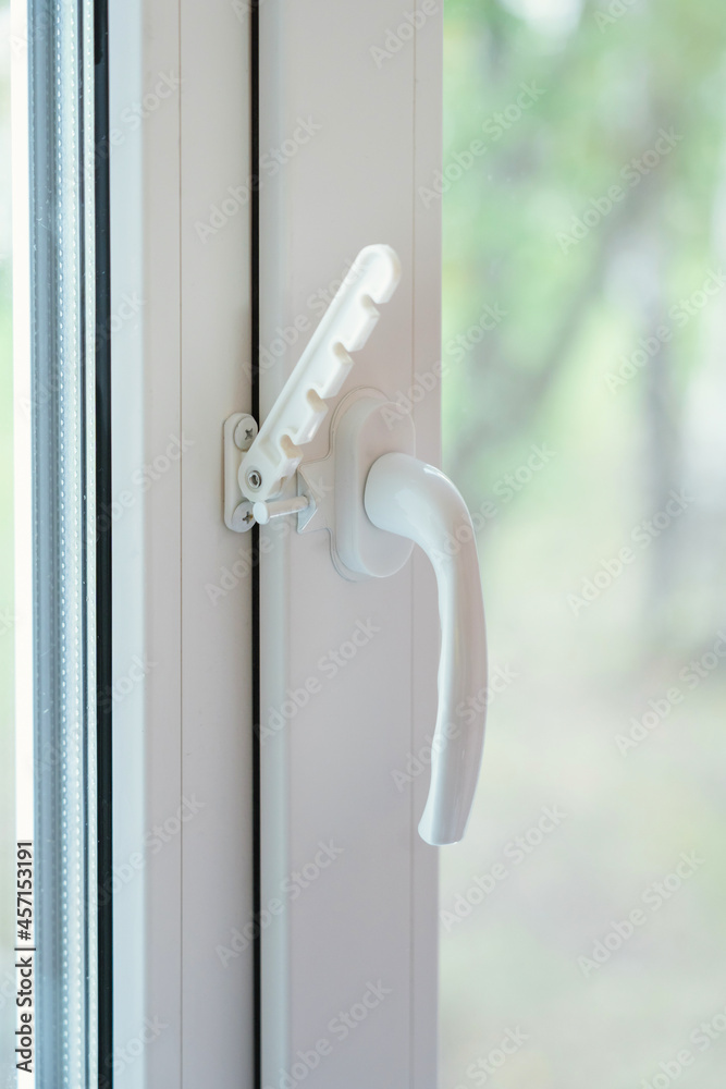 a white plastic handle on the window and an opening limiter. Closed pvc window
