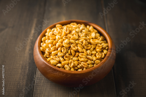 Wheat flakes cereal breakfast in wooden bowl on the rustic background. Selective focus.