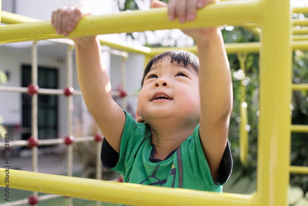Obraz premium little asian boy climbs up the ladder on the playground