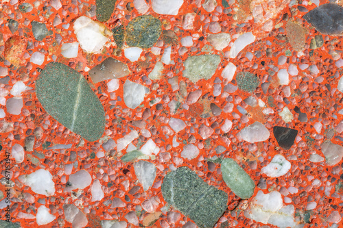 Natural stone background. A full-screen close-up texture of a red conglomerate (gravelite) with white and green grains.