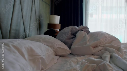 Positive Asian woman wake up on bed stretching. Women wake up feeling happy and fresh enjoying in the morning. Happy sleepy young adult woman waking up lying in comfortable white bed