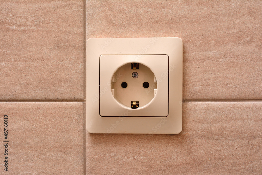 Electric socket on a tiled wall, close-up Electric socket on a tiled wall, close-up