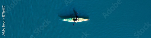 Obraz na płótnie View from above, aerial view of a person paddling a canoe - kayak on the Cedrino Lake surrounded by the mountain range of Supramonte located northeast of the Gennargentu massif. Sardinia, Italy. w salonie