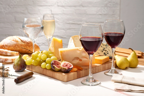 Mesa com tábua de queijos e frutas, acompanhados de diferentes vinhos