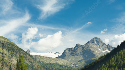 Blue sky with white clouds over italian alps and mountain peaks. On the left the glacier named "Rutor" in Aosta Valley, Italy.