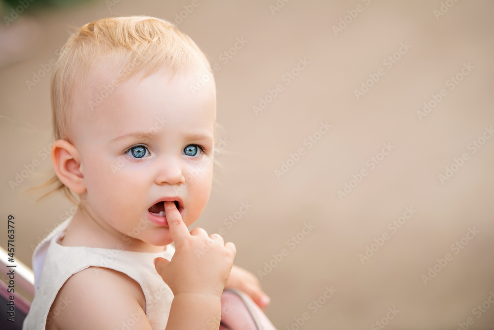 Portrait of blue-eyed baby sucking finger in her mouth, two first teeth are visible. Portrait of blue-eyed baby sucking finger in her mouth, two first teeth are visible.
