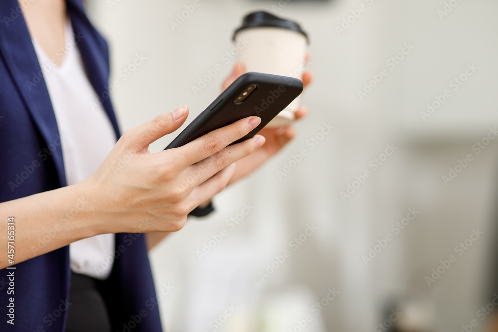Close up of young woman is using an app in her smartphone device,.hand holding morning coffee and reading phone.