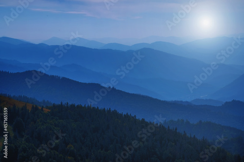 High peaks of beautiful dark blue mountain range landscape with fog and forest. Ukraine, Carpathians. Horizontal image. © zwiebackesser