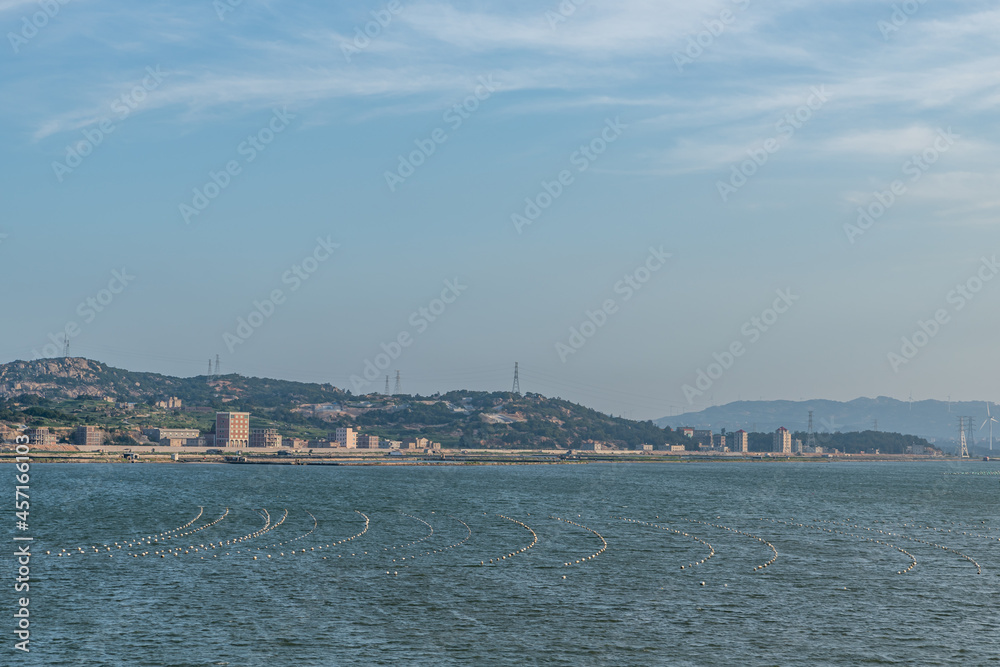 Under the blue sky, across the sea are mountains and wind power