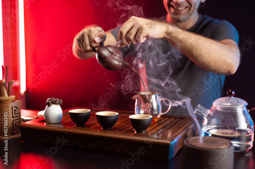 a man makes tea at a tea table with appliances according to the traditional Chinese tradition