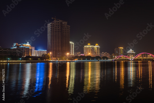 In the city at night, colorful lights are reflected in the water of the river © chen