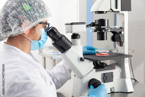 Young female scientist looking at samples under the microscope photo