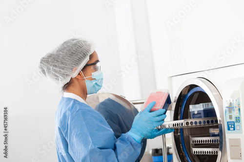 Young female scientist sterilizing laboratory material in autoclave photo