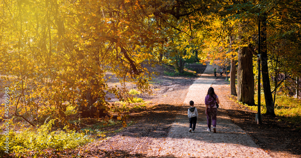 mom and son are walking in the park in the fall