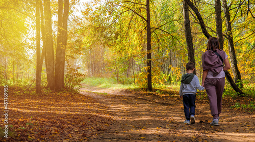 mom and son are walking in the park in the fall