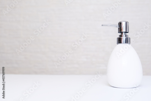 White liquid soap, body lotion dispenser on light background of bathroom with copy space