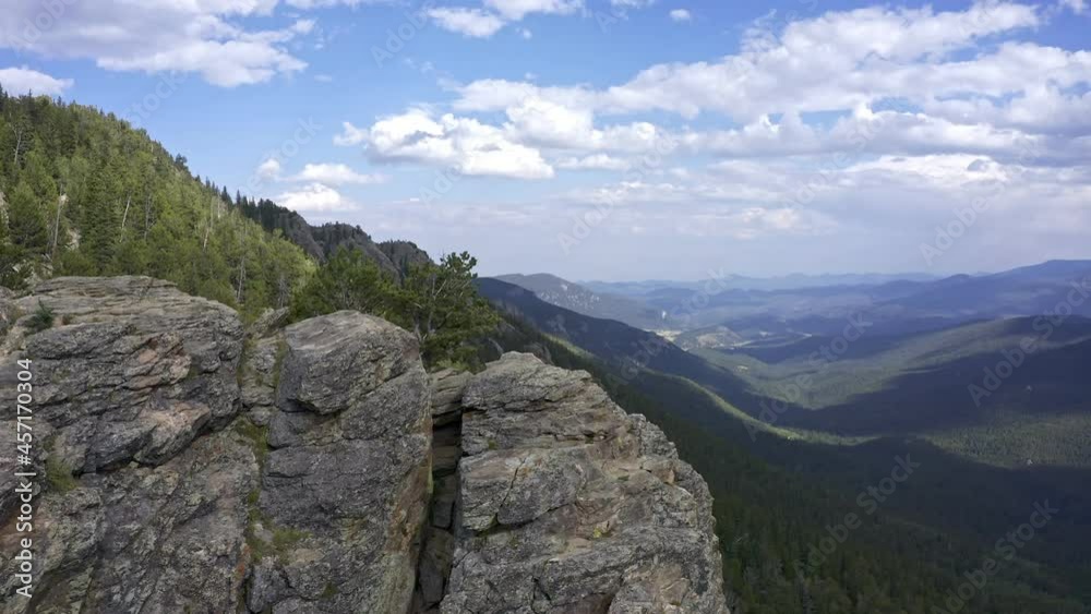 Flight over rugged, rocky cliff face, looking out over valley with forest of conifer trees, captured by a drone in 4K resolution near Juniper Point in the Rocky Mountains of Colorado. Flight over rugged, rocky cliff face, looking out over valley with forest of conifer trees, captured by a drone in 4K resolution near Juniper Point in the Rocky Mountains of Colorado.