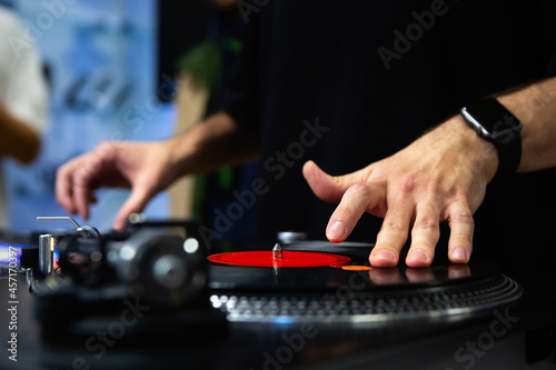 Hip hop dj scratching vinyl records on stage. Professional disc jockey scratches analog record with turn table and sound mixer devices
