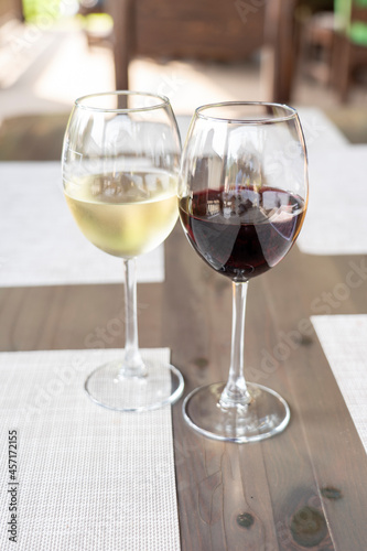 a glass of fragrant white and a glass of ruby red wine on a wooden table in a restaurant, selective focusing, dry white wine in a glass and semi-sweet red, expensive wine