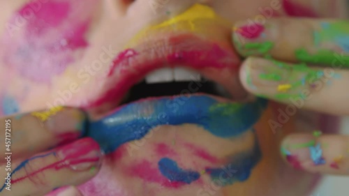 Close-up of female lips painted in different colors of rainbow. Woman sensually puts colours on her face using fingers to get extremely colorful makeup. 4k footage