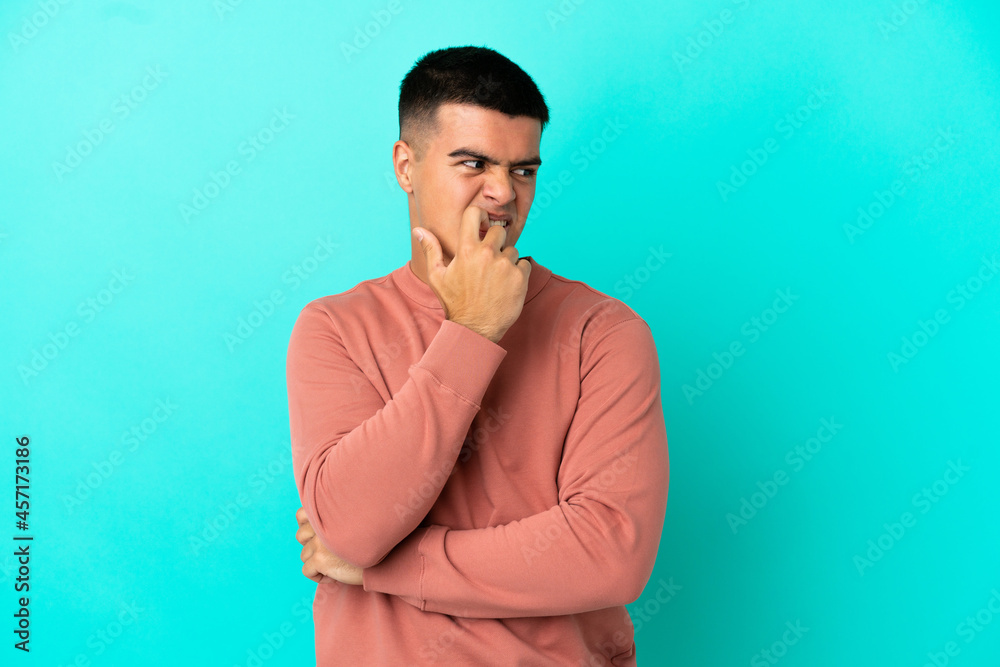 Young handsome man over isolated blue background nervous and scared