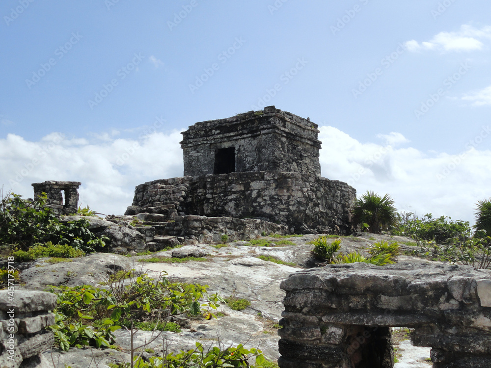 Ancient maya ruins at the archaeological zone at Tulum, Mexico, under a blue sky.