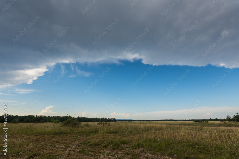dark rain front with blue sky with a flat landscape