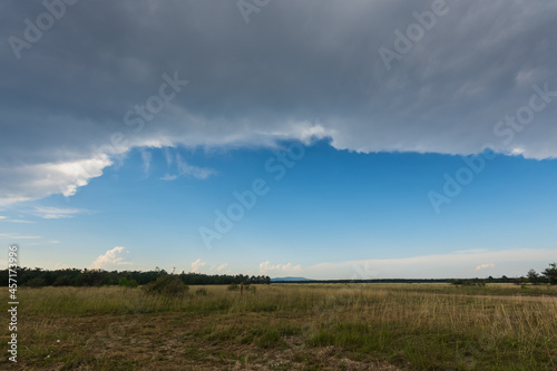 Fototapeta Naklejka Na Ścianę i Meble -  dark rain front with blue sky with a flat landscape