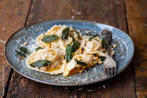 Home made pumpkin ravioli with crispy sage leaves and pinenuts photo