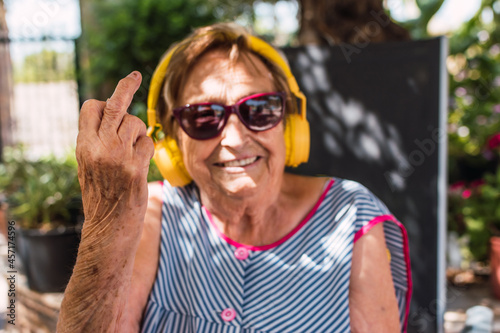 Elderly woman in bokeh smiling while raising a finger defiantly photo