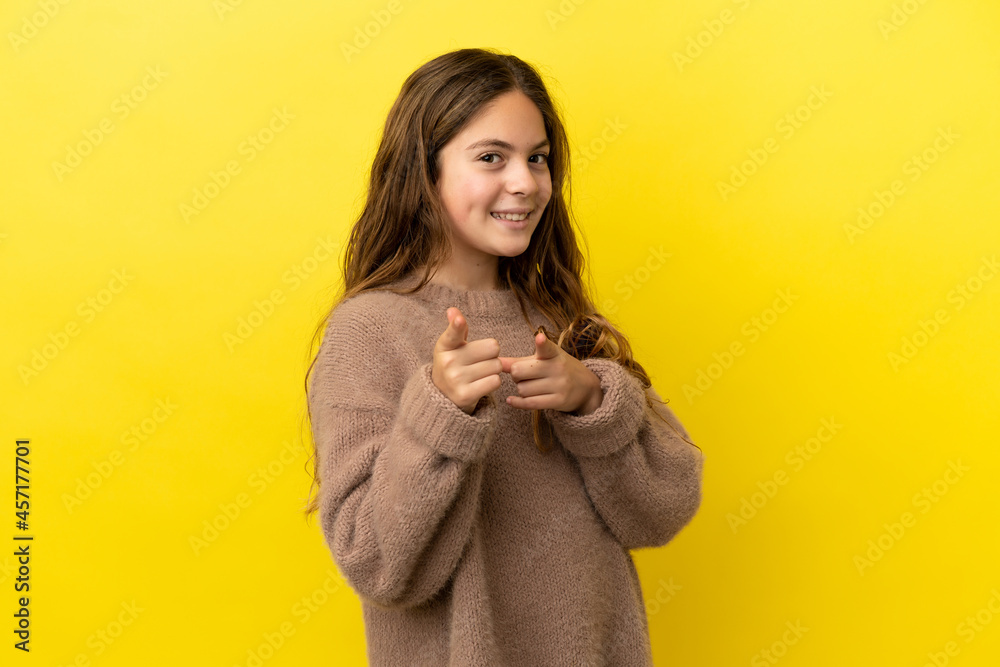 Little caucasian girl isolated on yellow background surprised and pointing front Little caucasian girl isolated on yellow background surprised and pointing front