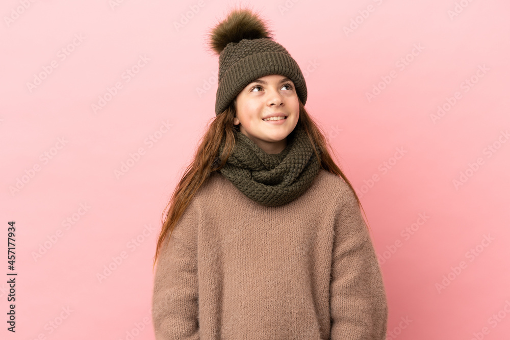 Little girl with winter hat isolated on pink background thinking an idea while looking up Little girl with winter hat isolated on pink background thinking an idea while looking up