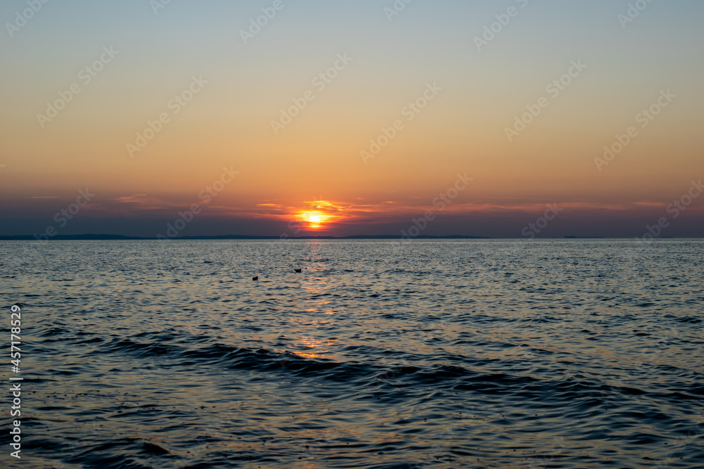 the setting sun against the backdrop of a calm sea