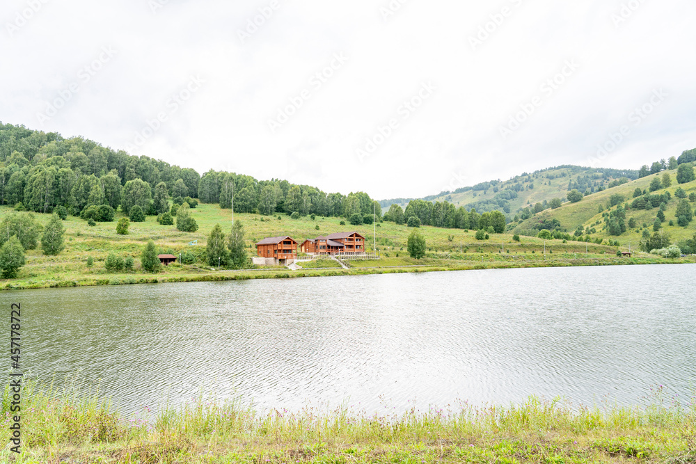 wooden house on the lake shore in the mountains, recreation center by the lake, cottages on the shore of a picturesque lake, rest in a country house by the water